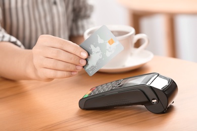 Woman using terminal for credit card payment in cafe