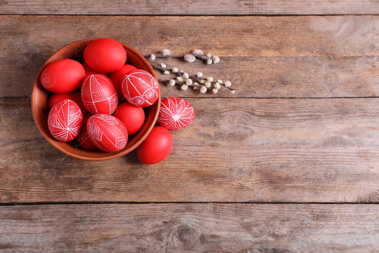 Photo of Bowl with red painted Easter eggs on wooden background, top view. Space for text