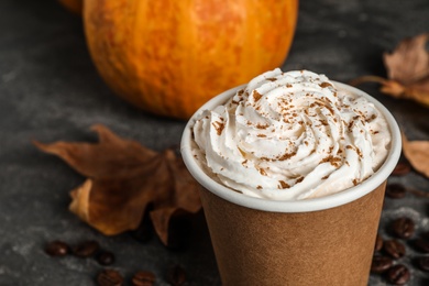 Photo of Paper cup with tasty pumpkin spice latte on grey table, closeup