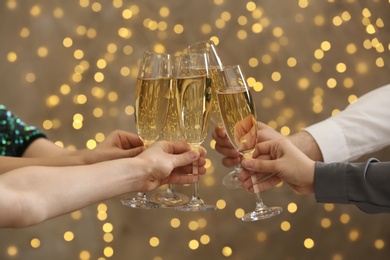 People clinking glasses of champagne on blurred background, closeup