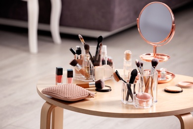 Makeup accessories and cosmetic products on table against blurred background