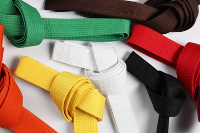Photo of Colorful karate belts on white background, flat lay