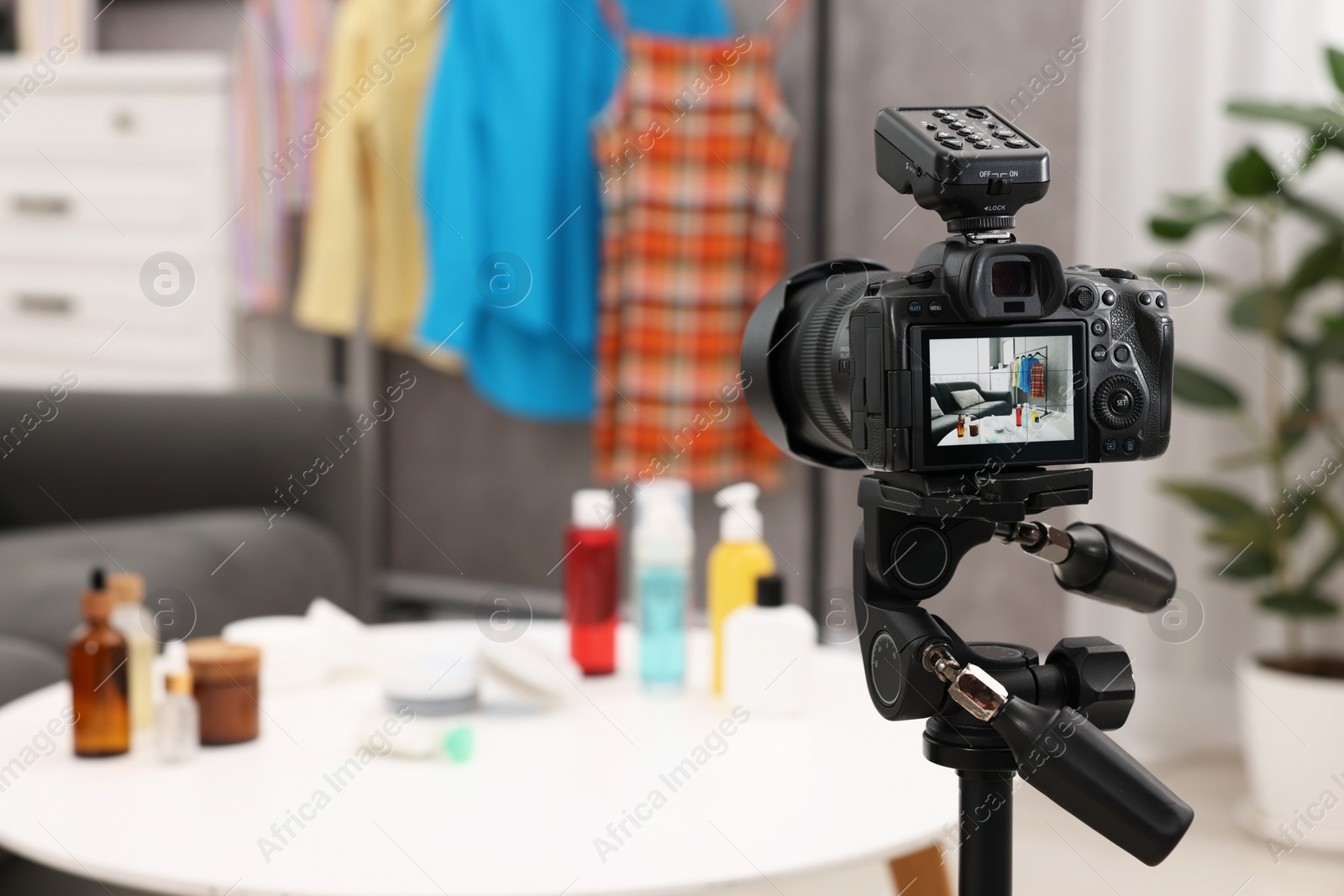 Photo of Beauty blogger's workplace. Cosmetic products and clothes indoors, focus on camera