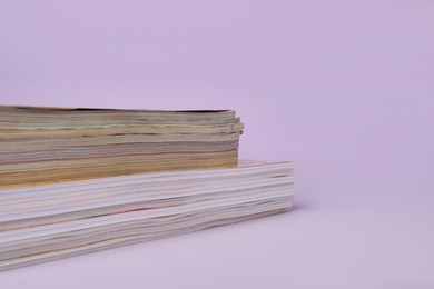Many stacked magazines on violet background, closeup. Space for text