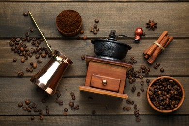 Photo of Vintage manual coffee grinder, beans, powder, cinnamon and jezve on wooden table, flat lay