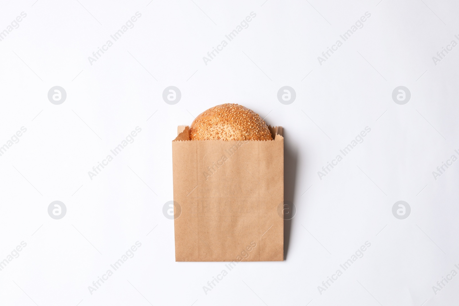 Photo of Paper bag with sesame bun on white background, top view. Space for design