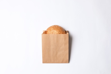 Photo of Paper bag with sesame bun on white background, top view. Space for design