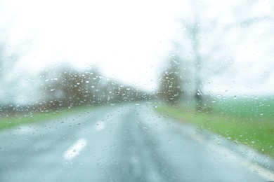 Photo of Blurred view of suburban road through wet car window. Rainy weather
