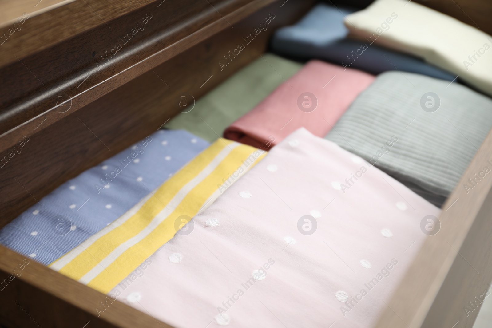 Photo of Chest of drawers with different folded clothes, closeup