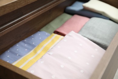 Photo of Chest of drawers with different folded clothes, closeup