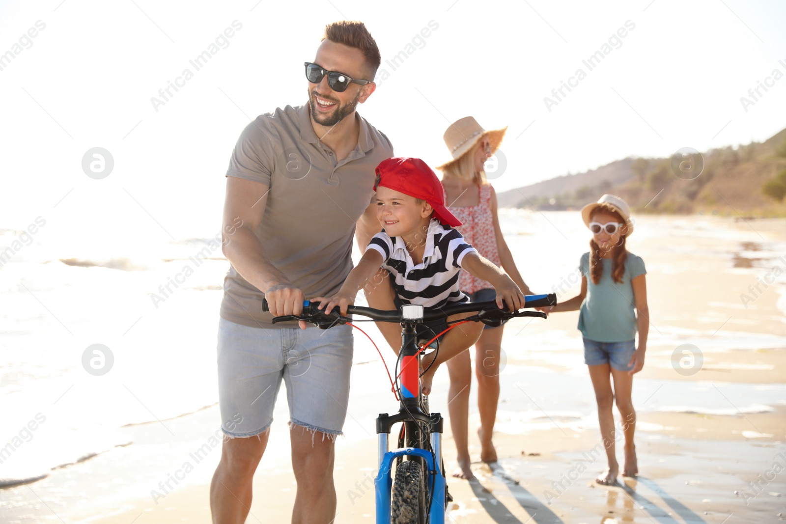 Photo of Happy family with bicycle on sandy beach near sea