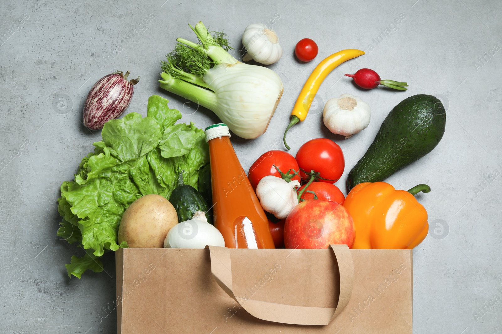 Photo of Overturned paper bag with bottle of juice, vegetables and fruits on grey background, flat lay