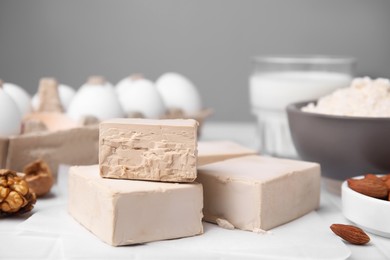 Photo of Blocks of compressed yeast and ingredients for dough on white table, closeup