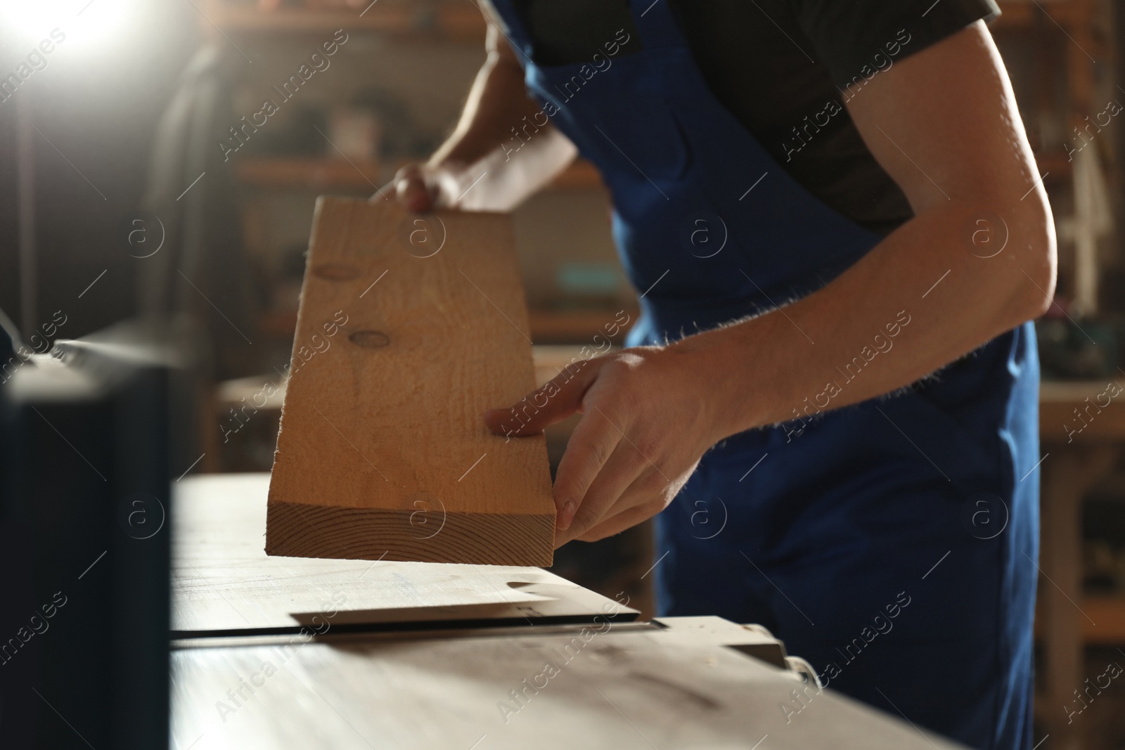 Photo of Professional carpenter working with wood in shop, closeup