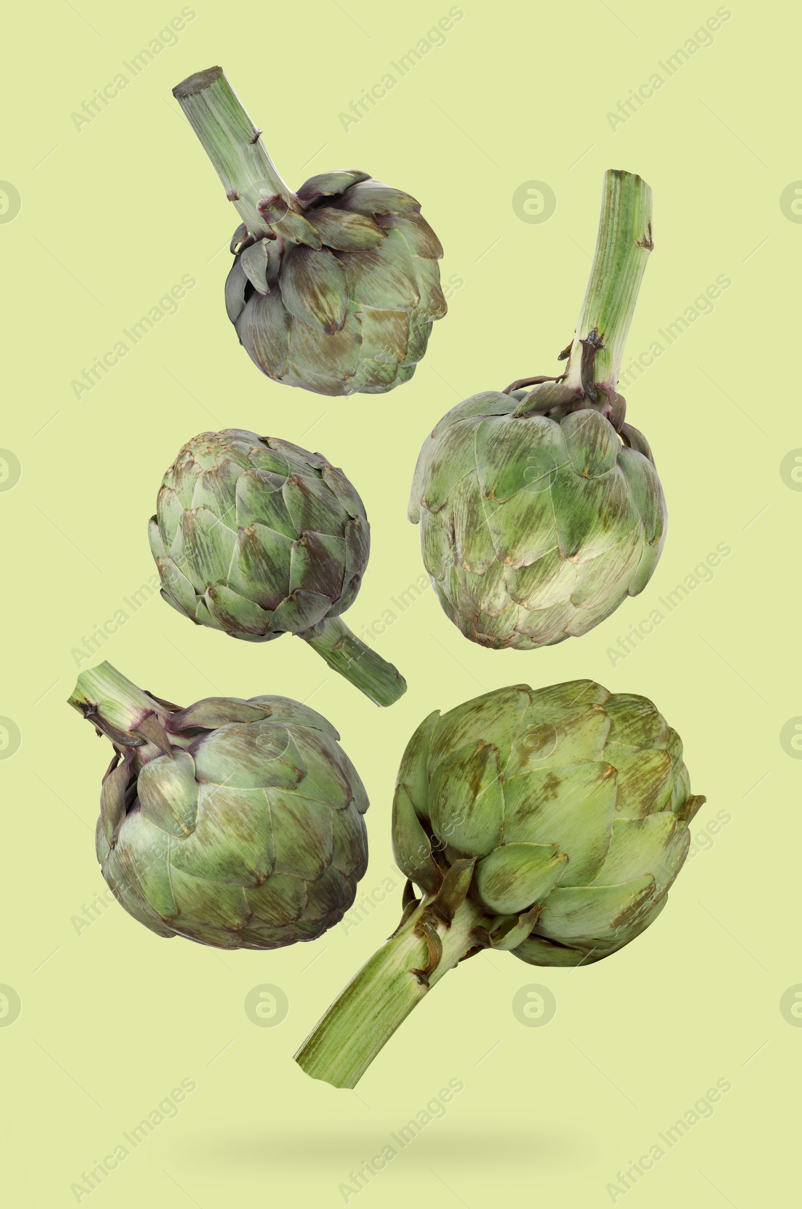 Image of Fresh raw artichokes falling on green background