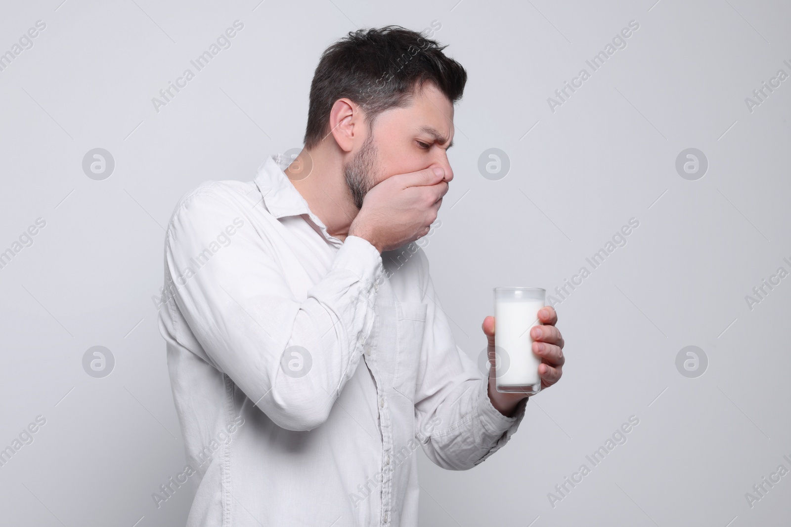 Photo of Man with glass of milk suffering from lactose intolerance on white background