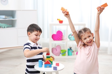 Photo of Cute children playing with colorful blocks at home