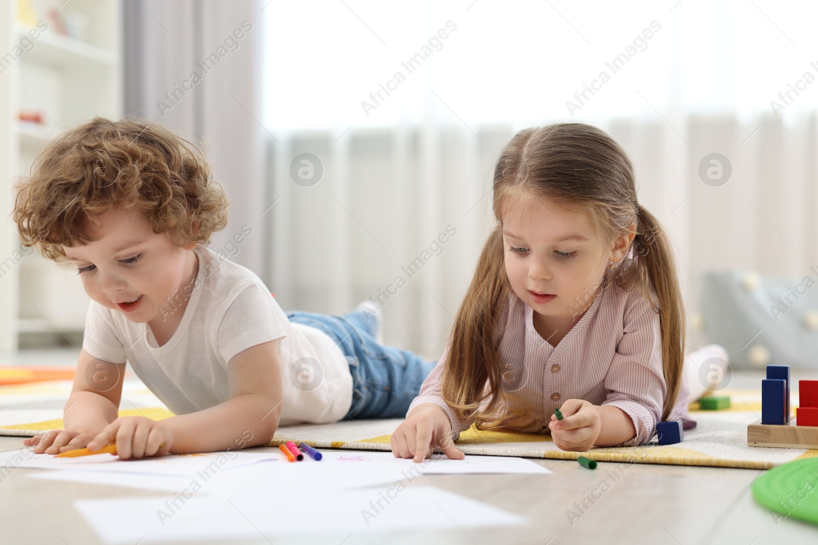 Photo of Cute little children drawing on floor in kindergarten