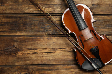 Photo of Classic violin and bow on wooden background, top view. Space for text