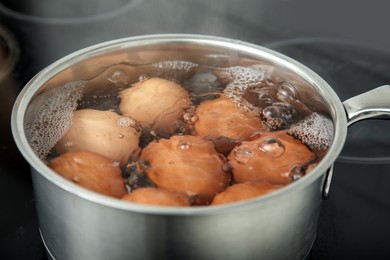 Boiling chicken eggs in saucepan on electric stove, closeup