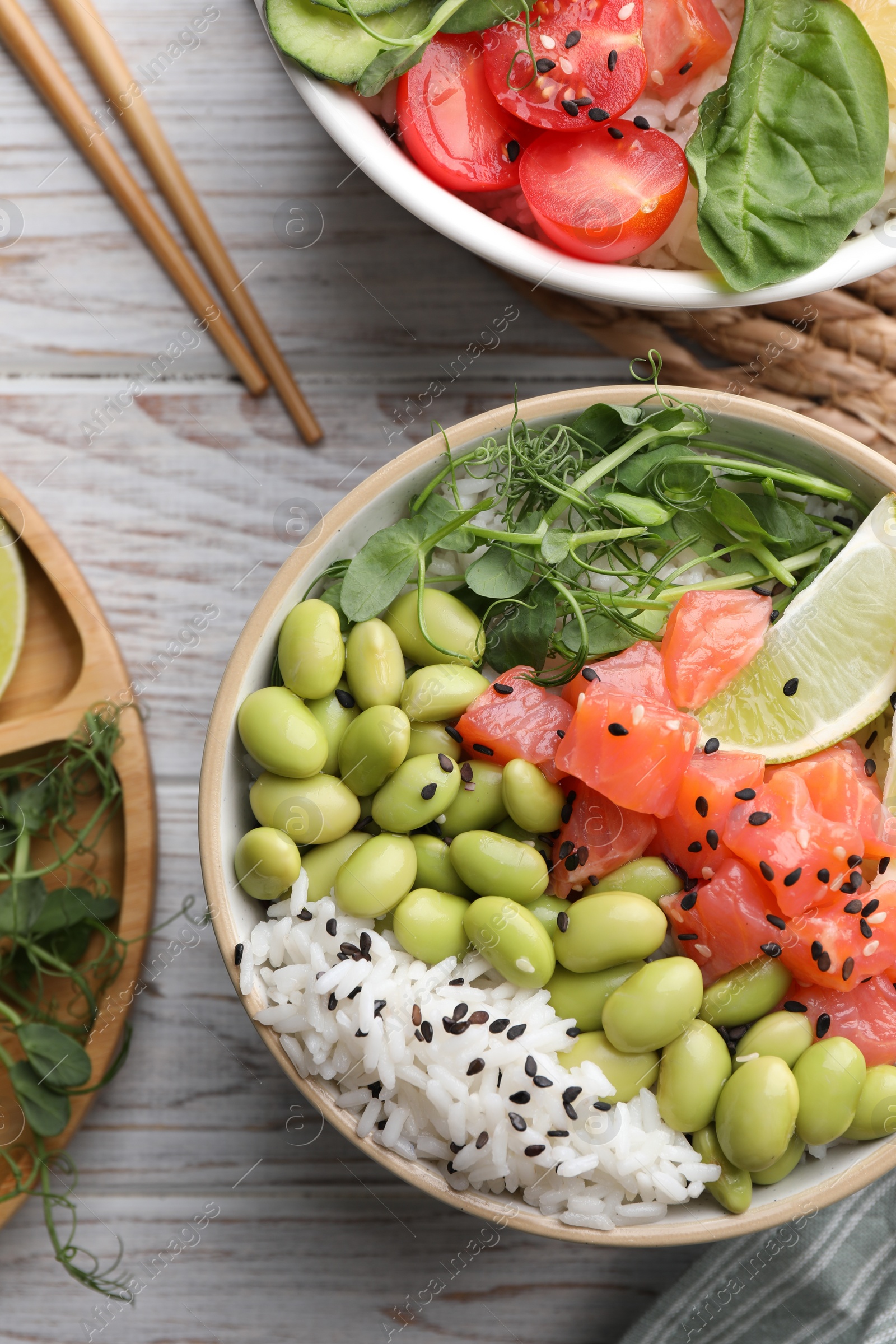 Photo of Delicious poke bowls with fish and edamame beans on white wooden table, flat lay