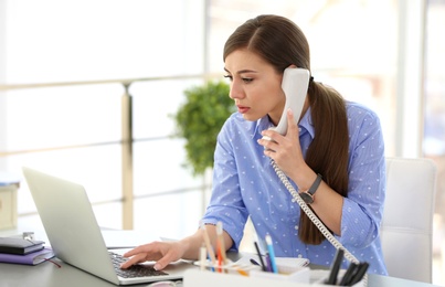 Young woman talking on phone at workplace