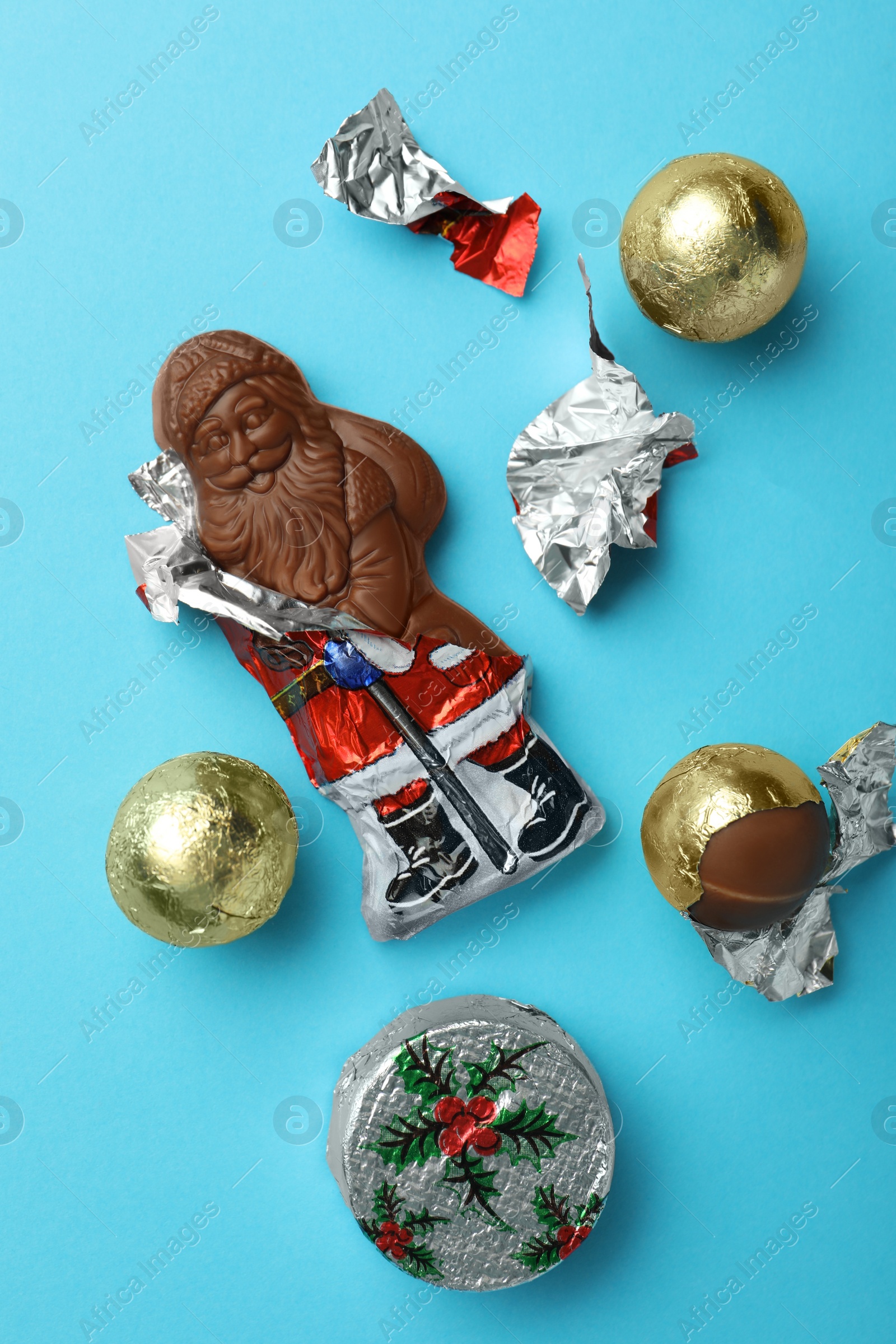 Photo of Chocolate Santa Claus and sweets on light blue background, flat lay