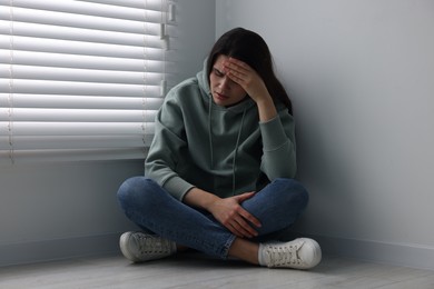 Photo of Sadness. Unhappy woman sitting on floor at home