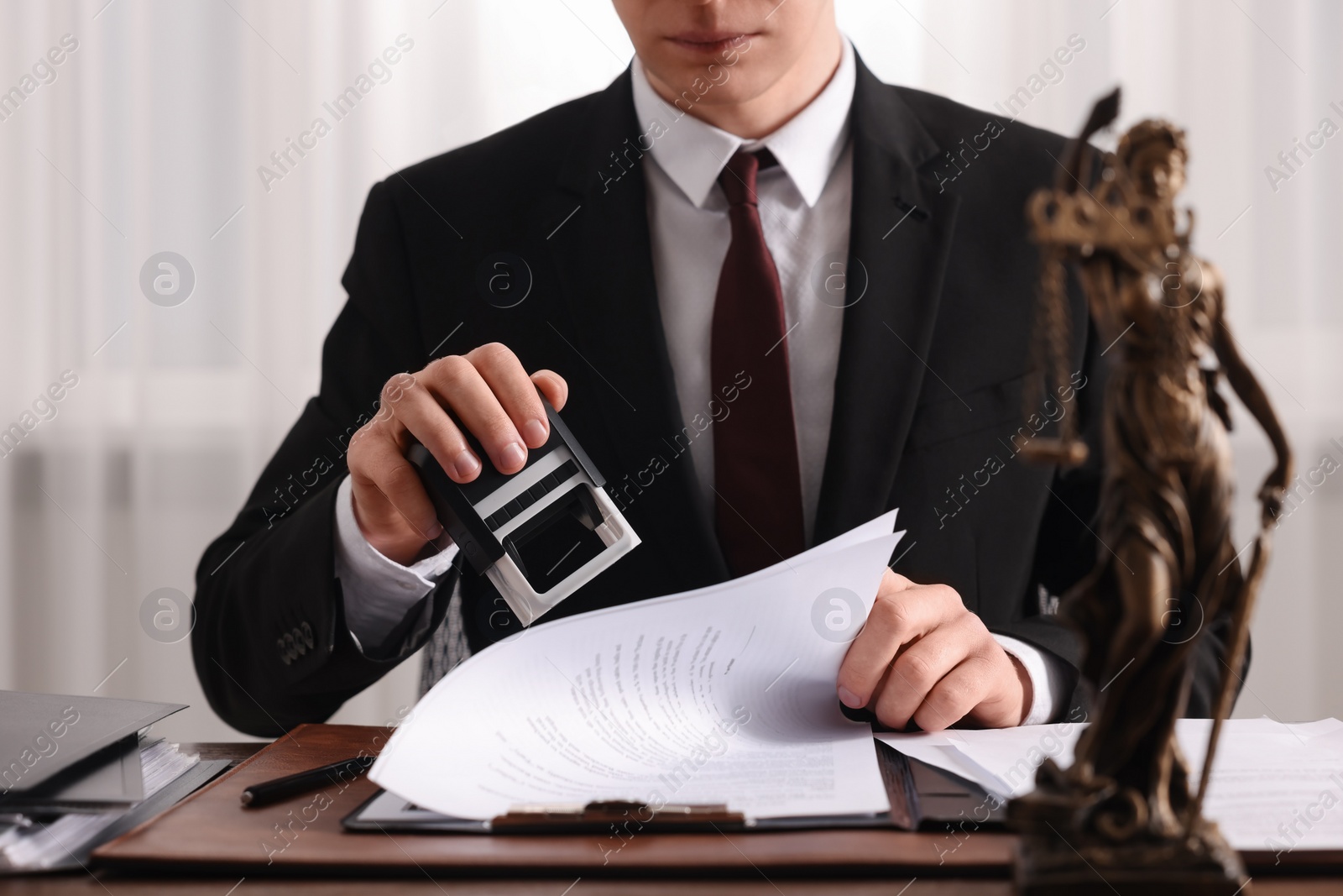 Photo of Notary stamping document at table in office, closeup