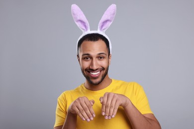 Happy African American man in bunny ears headband on gray background