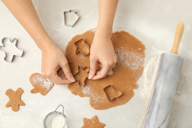 Woman making Christmas cookies at light table, top view