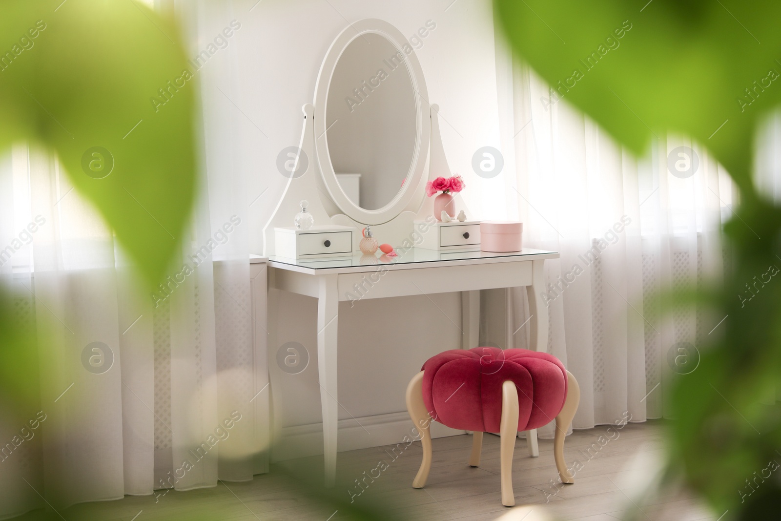 Photo of Elegant white dressing table and pouf in light room