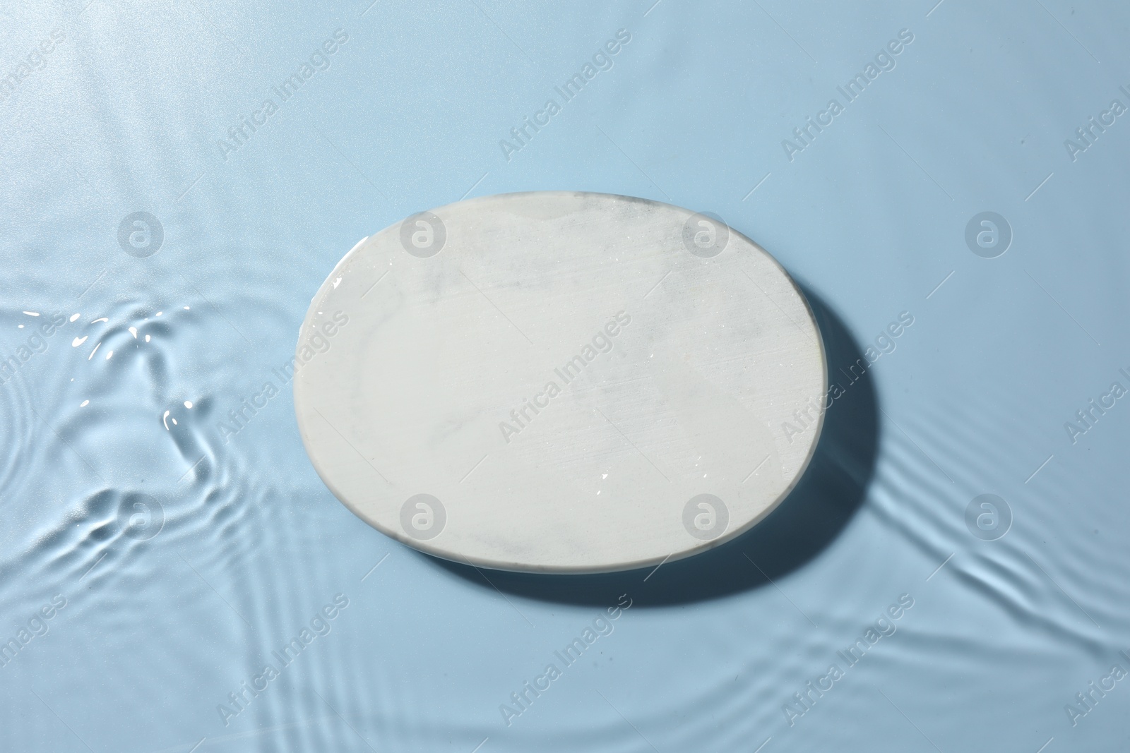 Photo of Presentation for product. White podium in water on light blue background, top view