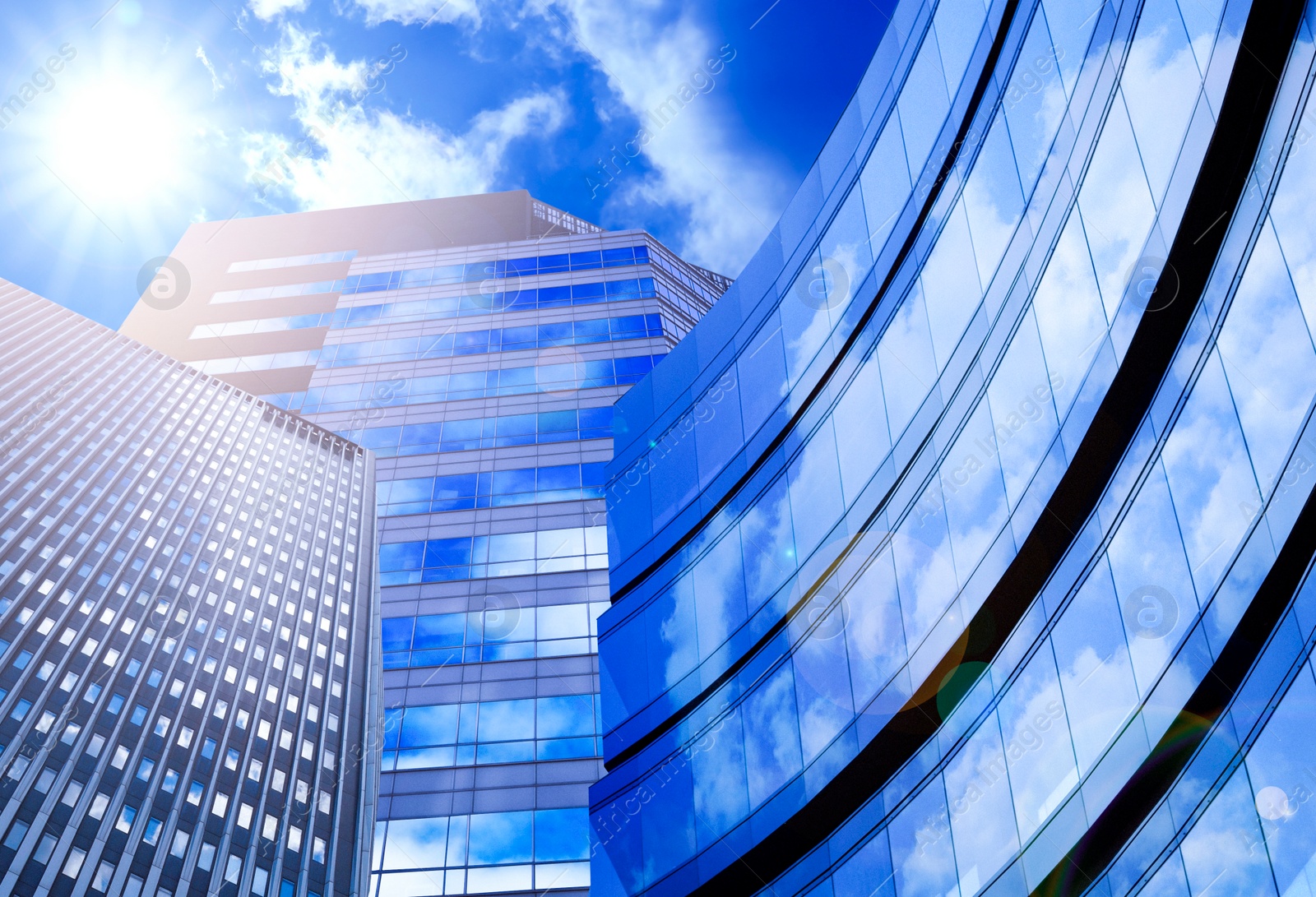 Image of Beautiful blue sky with clouds reflecting in windows. Low angle view of modern buildings on sunny day