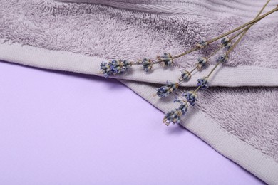 Photo of Terry towel and lavender flowers on violet background, closeup. Space for text