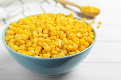 Photo of Delicious canned corn in bowl on white wooden table, closeup