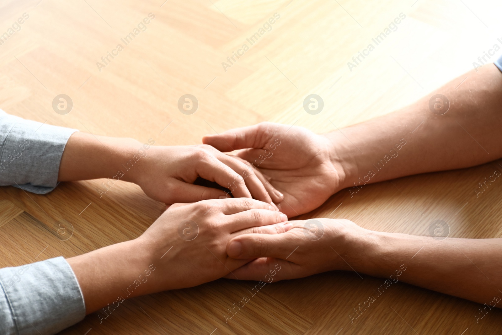 Photo of Young people holding hands on wooden background, closeup. Happy family