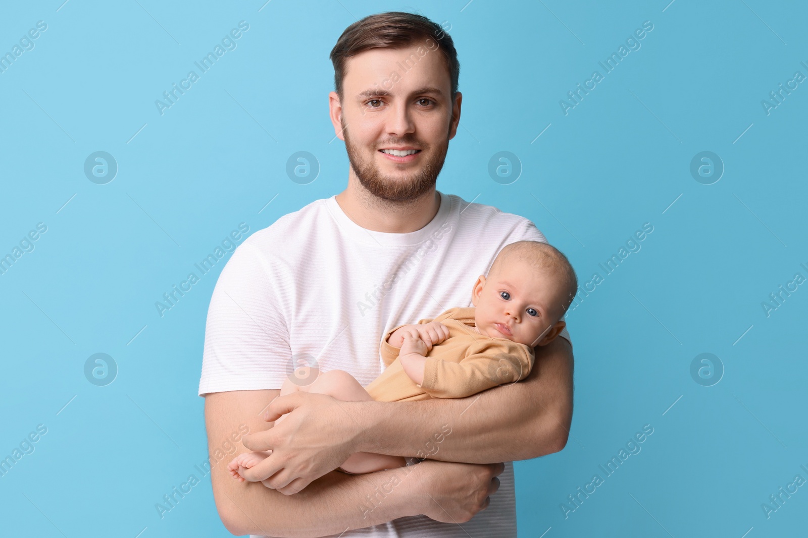 Photo of Father with his cute baby on light blue background