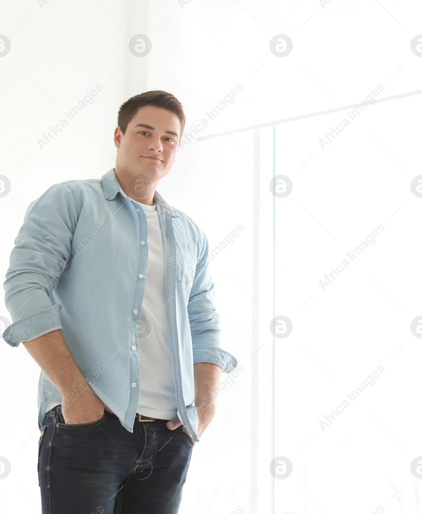 Photo of Portrait of confident young man near window, indoors