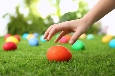 Photo of Little child taking Easter egg from green grass, closeup