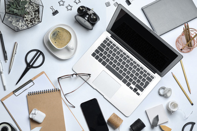 Flat lay composition with laptop, smartphone and stationery on white table. Designer's workplace