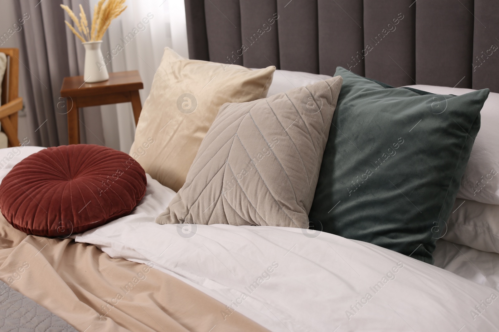 Photo of Large comfortable bed with soft pillows and blanket in room. Home textile