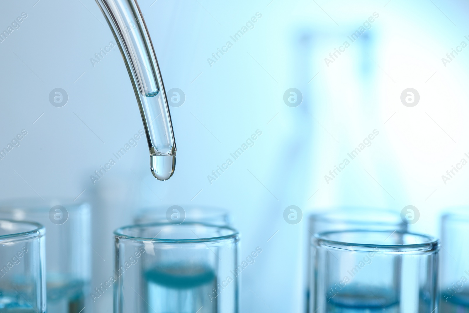 Photo of Dripping liquid into test tube, closeup with space for text. Solution chemistry