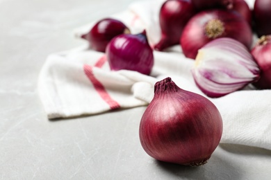 Photo of Fresh whole red onion bulbs on marble table. Space for text