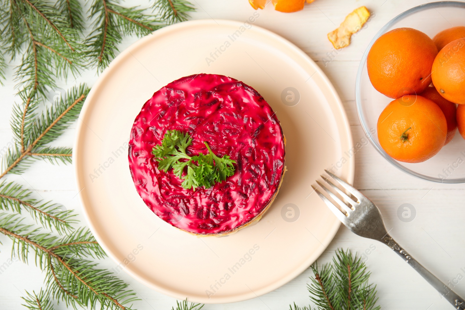 Photo of Flat lay composition with herring under fur coat, tangerines and fir branches on white wooden table. Traditional russian salad