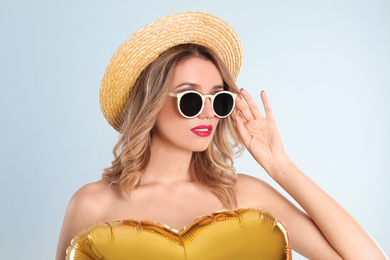 Young woman wearing stylish sunglasses and hat on light grey background