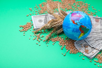 Photo of Import and export concept. Globe, ears of wheat, grains and banknotes on green background. Space for text
