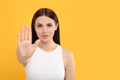 Photo of Woman showing stop gesture on orange background, space for text