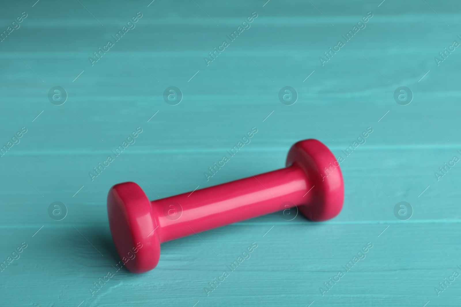 Photo of Pink vinyl dumbbell on turquoise wooden table