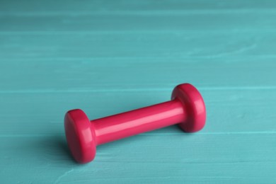 Photo of Pink vinyl dumbbell on turquoise wooden table